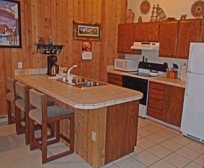 Kitchen features a central island with sink and stovetop, microwave, dishwasher, and refrigerator.