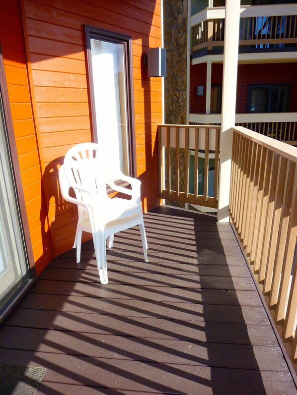 Relax on the deck with a chair, surrounded by a railing and a stone accent wall.