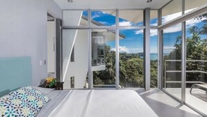 A modern bedroom with a large bed, a view of the outdoors, and a balcony. - Private Eco-Villa, Prime Central Location, Ocean Views, Wildlife, and Nightlife (Quepos)