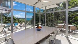 A spacious room with large windows offering a view of a pool and lush greenery. - Private Eco-Villa, Prime Central Location, Ocean Views, Wildlife, and Nightlife (Quepos)
