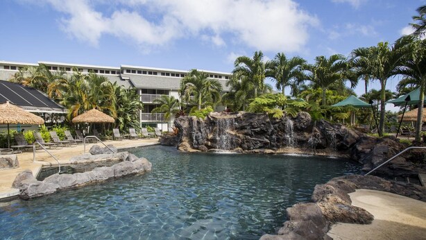 A resort pool with clear water, lounge chairs, and a waterfall feature. - Amazing Kauai 2 BR Condo Ocean View (Princeville)