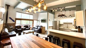 Amplia sala de estar con una mesa de comedor de madera, sofás de cuero y un gran ventanal que proporciona luz natural.