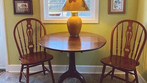 Una mesa de comedor con dos sillas, una lámpara y cuadros en la pared.