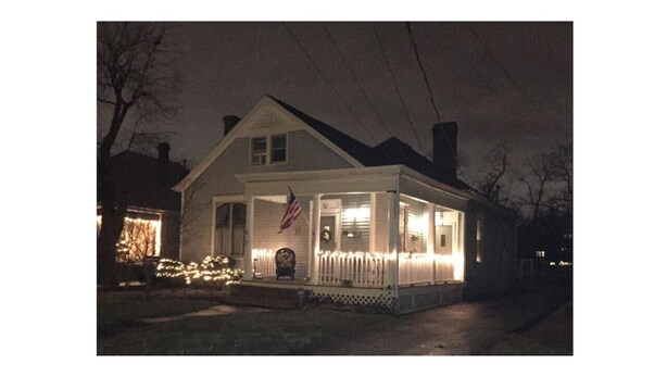 Una casa de dos pisos con porche, una bandera y luces.