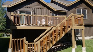Ein zweistöckiges Haus mit einer Holzterrasse und einer Treppe, die zum oberen Stock führt.