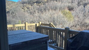 Eine Terrasse mit Whirlpool, Holzwerteln und Schnee auf dem Boden.