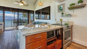 Cozinha com uma ilha grande, área de jantar com vista e varanda com mesa e cadeiras.