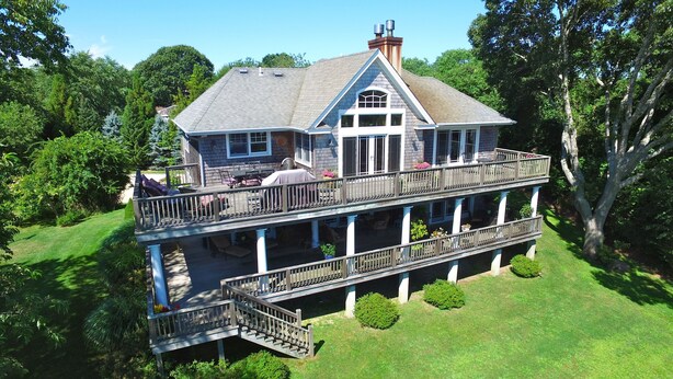 A two-story house with a balcony, a covered patio, and a well-maintained lawn. - Newly Built 3 Story Home with Beach Parking Pass (Montauk)