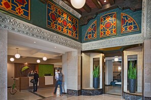 A lobby with a reception desk, a green wall, and two large potted plants.