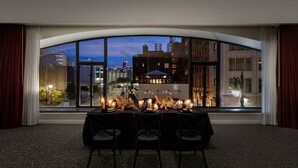 A dining area with a table set for four, a large arched window, and a cityscape view. - Element by Marriott Detroit at The Metropolitan (Detroit)
