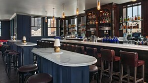 A bar area with a marble countertop, bar stools, and a variety of liquor bottles. - Element by Marriott Detroit at The Metropolitan (Detroit)