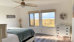A bedroom with a bed, a dresser, a ceiling fan, and a view of the beach. - Pacific Dreams Beach House- Beach front! Gorgeous views! Meticulously sanitized! (Grayland)