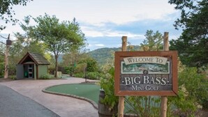Ein Willkommensschild für Big Bass Mini-Golf, im Hintergrund ein kleines Gebäude.