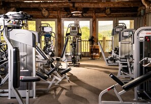 A gym with various exercise machines, a wooden ceiling, and a view of the outdoors. - Wilderness Club™ at Big Cedar® - 2 Bedroom Combined Lodge (Ridgedale)