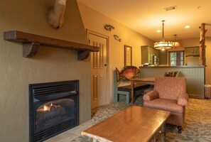 A cozy living room with a fireplace, a dining table, and a comfortable armchair. - Wilderness Club™ at Big Cedar® - 2 Bedroom Combined Lodge (Ridgedale)