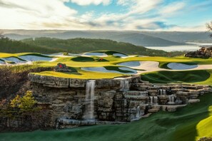 A golf course with a waterfall feature and a view of distant hills. - Wilderness Club™ at Big Cedar® - 2 Bedroom Combined Lodge (Ridgedale)