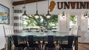 A dining area with a large table, black chairs, and hanging pendant lights.