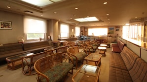 A spacious room with multiple seating areas, including sofas and chairs, arranged around a central table.