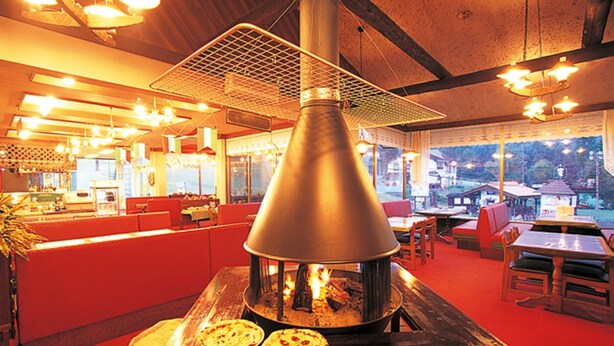 A restaurant with a wood-burning stove, red seating, and a view of the outdoors.