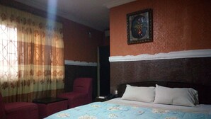 Un dormitorio con una cama, una silla, un televisor y un cuadro en la pared.