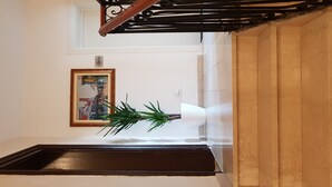 Een trap met een houten leuning en een witte muur met een schilderij in een lijst.
