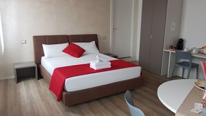 Een hotelkamer met een bed, een bureau, een stoel en een tafeltje.
