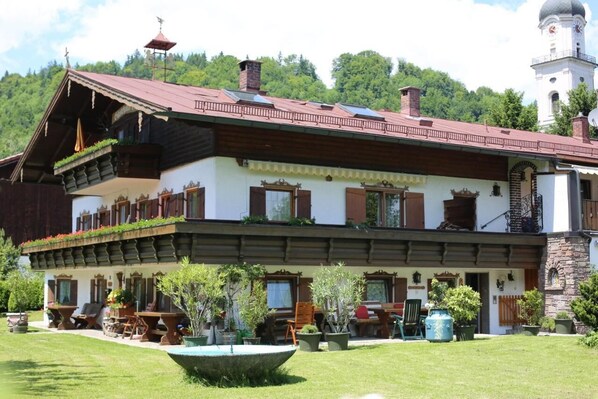 A traditional chalet with a sloped roof, wooden balconies, and a stone facade.