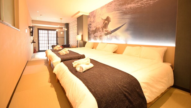 Una habitación de hotel con una cama grande, una cama más pequeña y un mural en la pared.