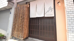 Entrada de un edificio con una persiana cerrada, una valla de bambú y un letrero con el texto '5STAR'.