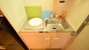 Cocina compacta con un lavamanos, tabla de cortar, balanza y una pequeña botella de jabón para manos.