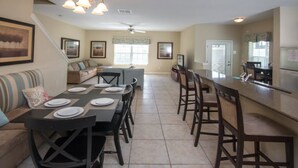 A spacious kitchen with a dining area, a bar, and a living room with a sofa and a coffee table.