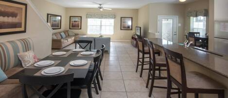 A spacious kitchen with a dining area, a bar, and a living room with a sofa and a coffee table.
