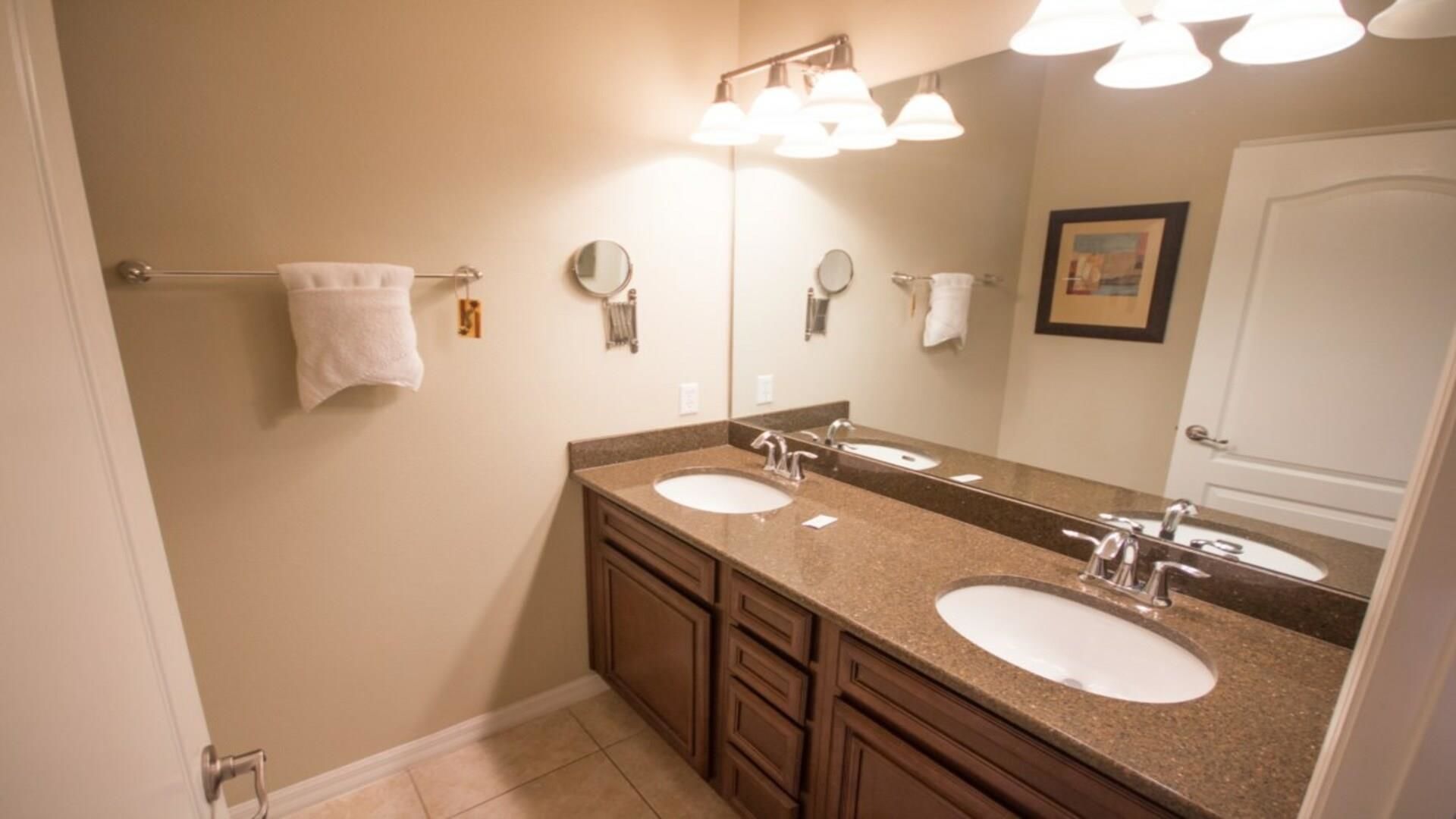 Un baño con dos lavamanos, un espejo grande y tres luces empotradas.