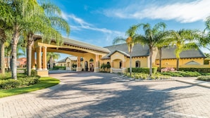 A hotel entrance with a paved driveway, palm trees, and a covered walkway.