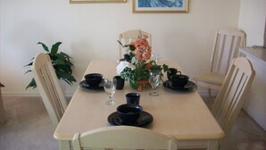Ein Esstisch, gedeckt mit schwarzen Tellern, Tassen und einer Blumenvase.