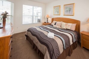 A bedroom with a large bed, a bedside table with a lamp, a dresser, and a window with blinds. - Ip60344 - Windsor Hills Resort - 5 Bed 5 Baths Villa (Kissimmee)
