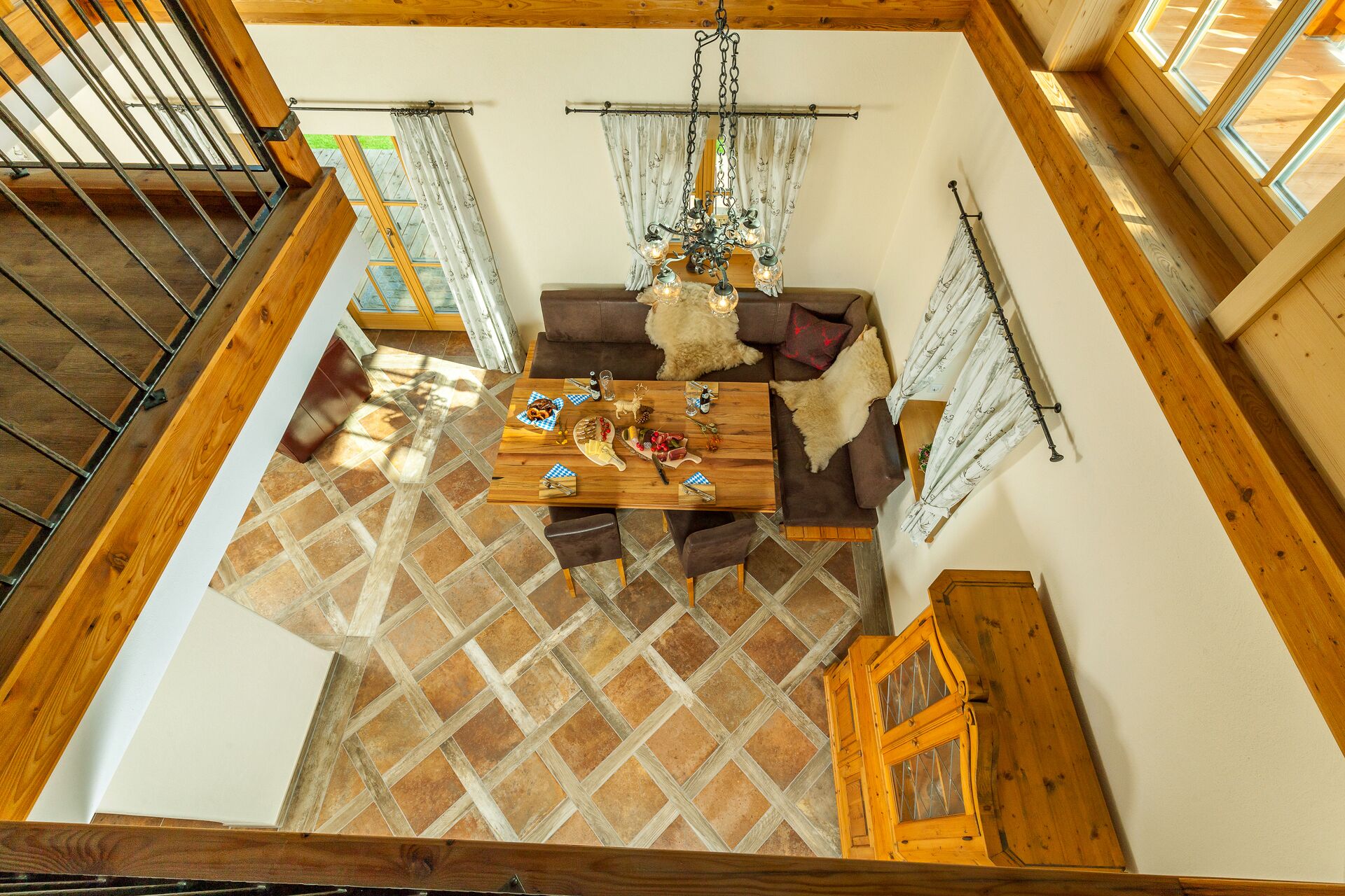 A dining area with a wooden table, brown leather sofa, and a chandelier.