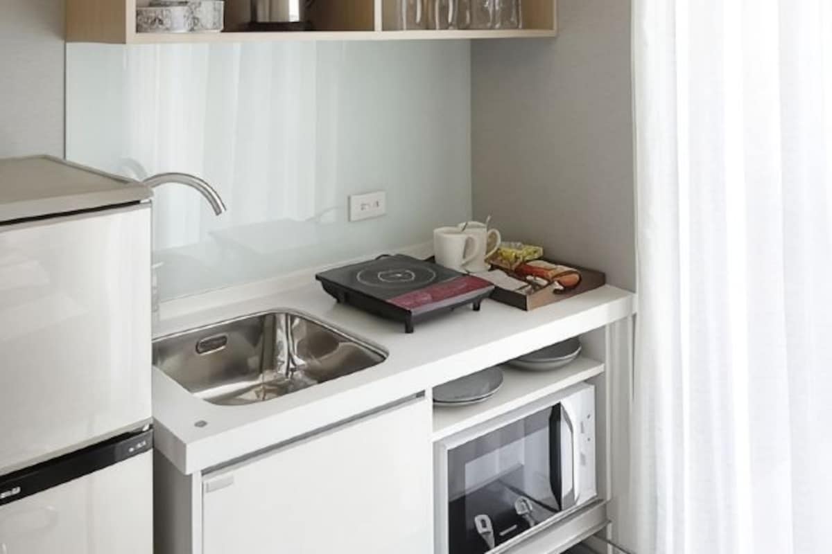 A compact kitchen with a sink, a stove, and a microwave.
