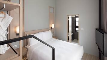 Una habitación de hotel con cama, mesitas de noche, televisión, espejo y armario.
