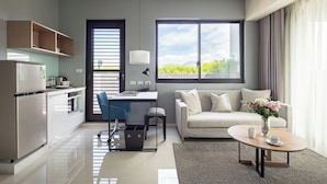 A modern living room with a sofa, coffee table, and a view of the outdoors. - Jolley Hotel (Taipei)