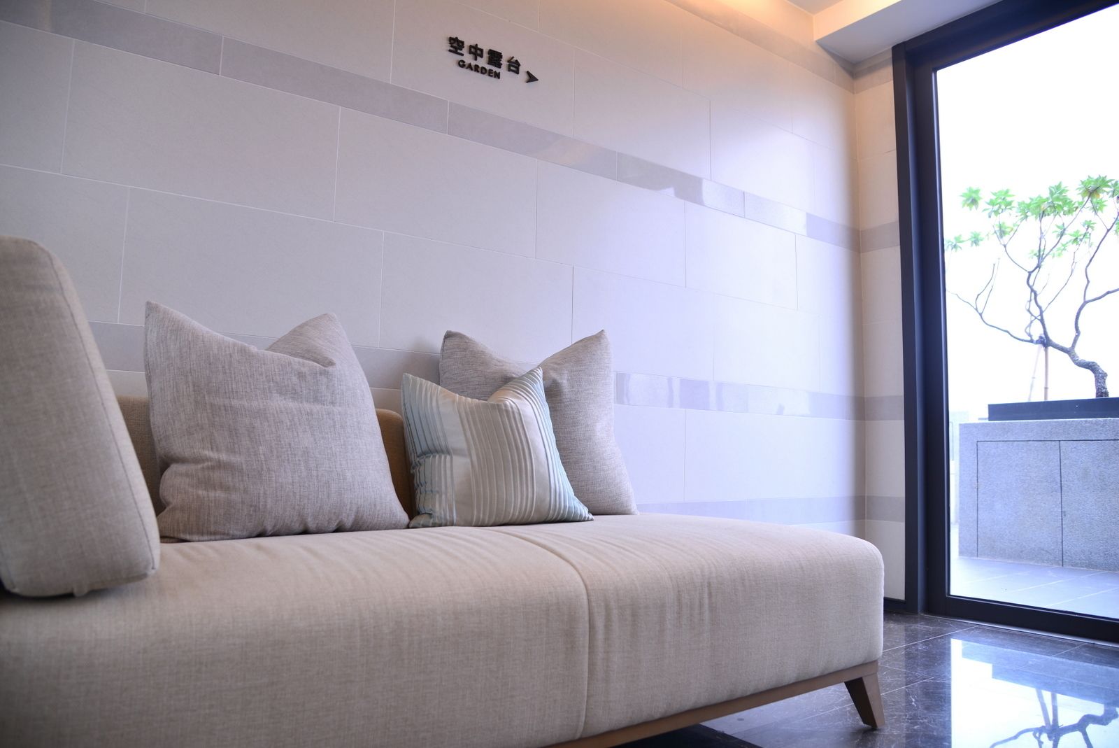 Una sala de estar moderna con un sofá, almohadones y un cartel que indica la dirección del jardín.