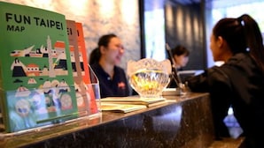 A reception desk with a map titled "FUN TAIPEI MAP" and a decorative glass bowl. - Jolley Hotel (Taipei)