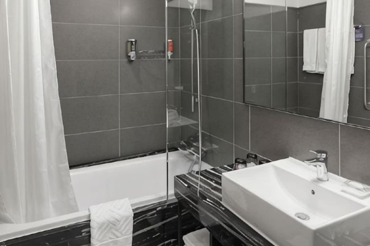 A modern bathroom with a glass-enclosed shower, a white sink, and a large mirror.