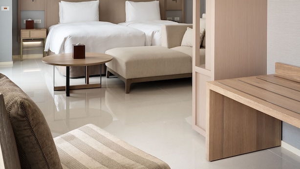 A modern hotel room with a large bed, a sofa, a small table, and a wooden partition. - Jolley Hotel (Taipei)