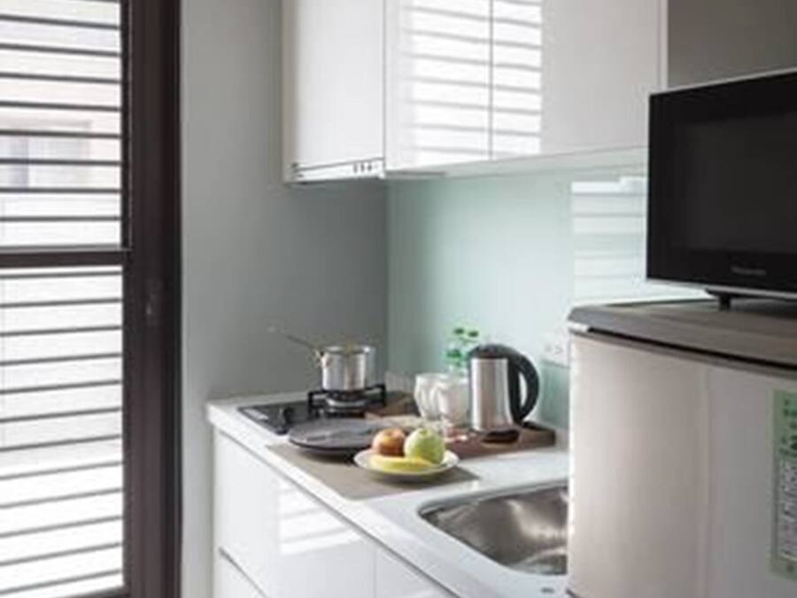A modern kitchen with white cabinetry, a stainless steel sink, and a black microwave.