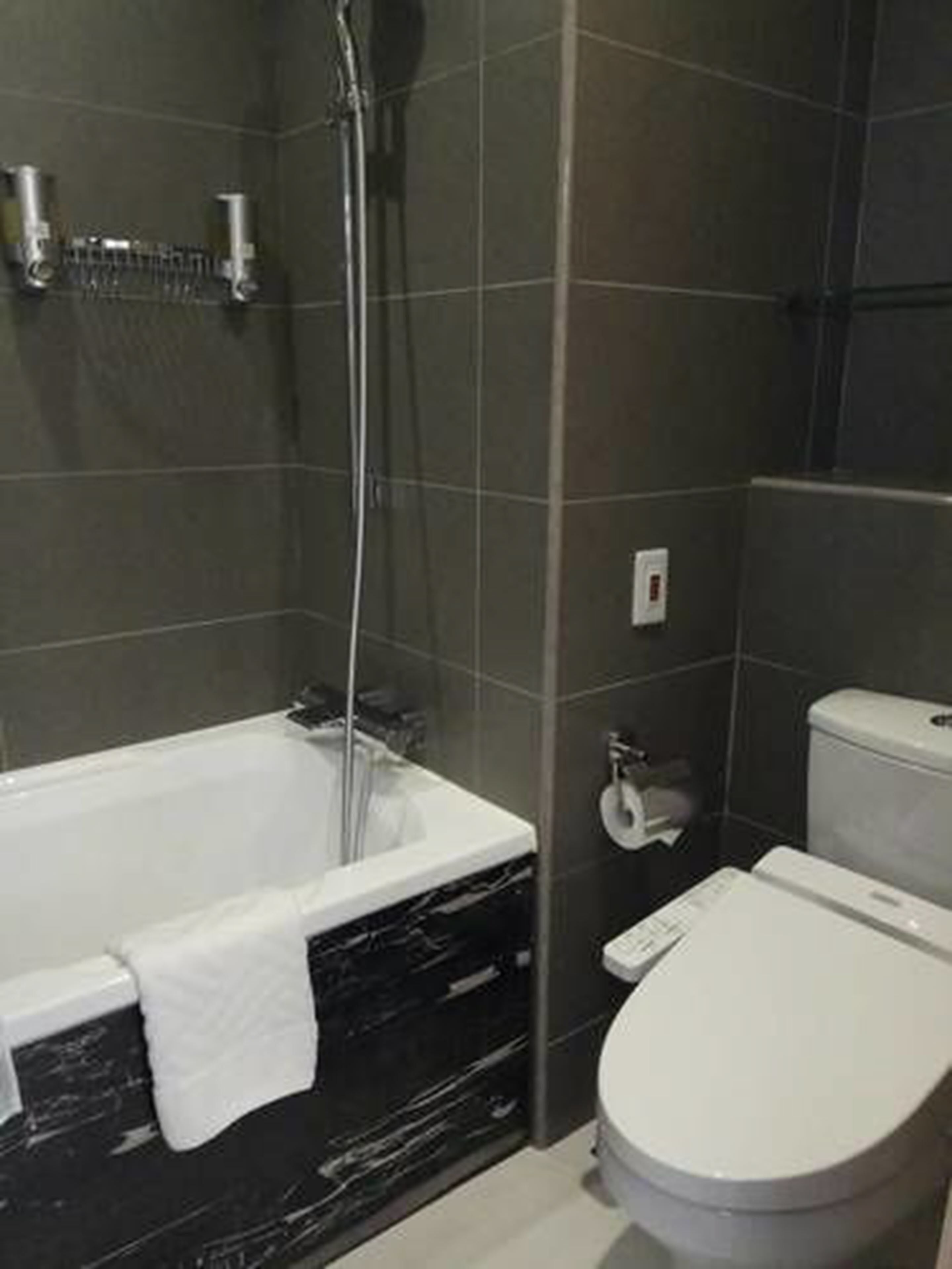 Et moderne badeværelse med badekar, toilet og brusebad.