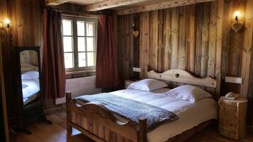 A wooden room with a bed, a mirror, and a nightstand.