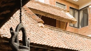 A traditional building with a tiled roof, a hanging lamp, and a person visible through a window. - Newa Chen Historic House UNESCO (Lalitpur)