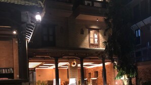 A courtyard with outdoor seating, a brick wall, and a staircase leading to an upper level. - Newa Chen Historic House UNESCO (Lalitpur)