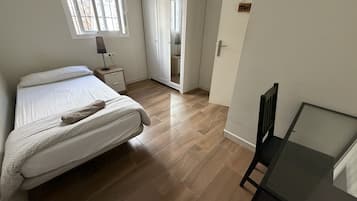 Un dormitorio con cama, mesita de noche, armario y escritorio con silla.
